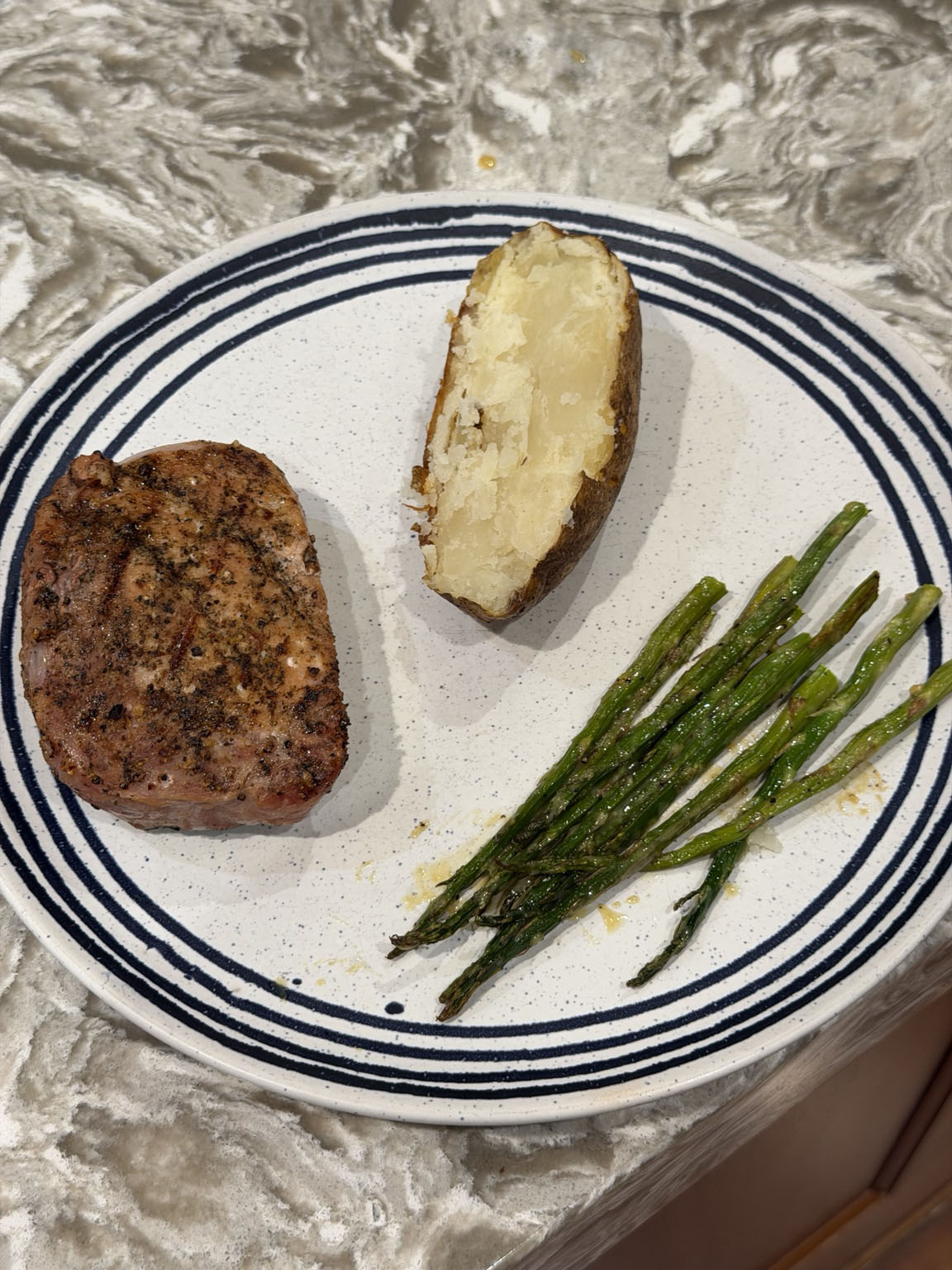 Bourbon-brined grilled pork chop served with a baked potato and roasted asparagus